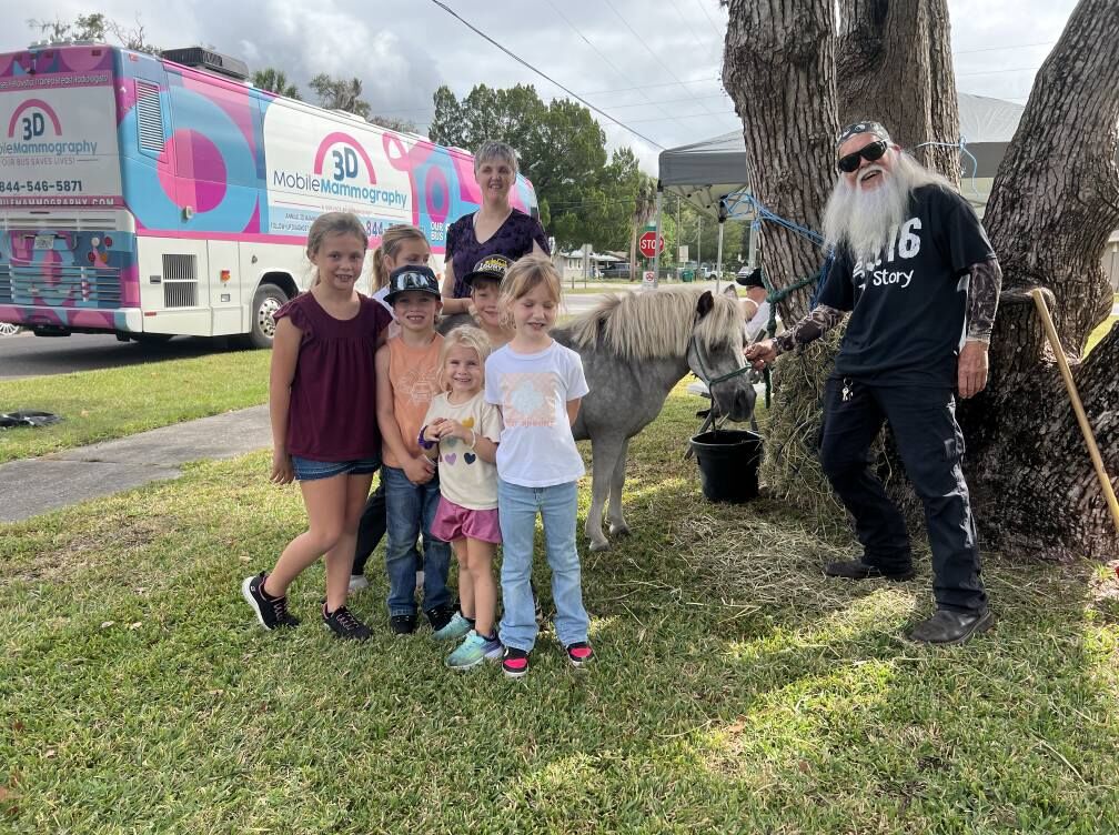 Children meet a miniature horse beside the mobile mammography bus at the Health & Wellness Day